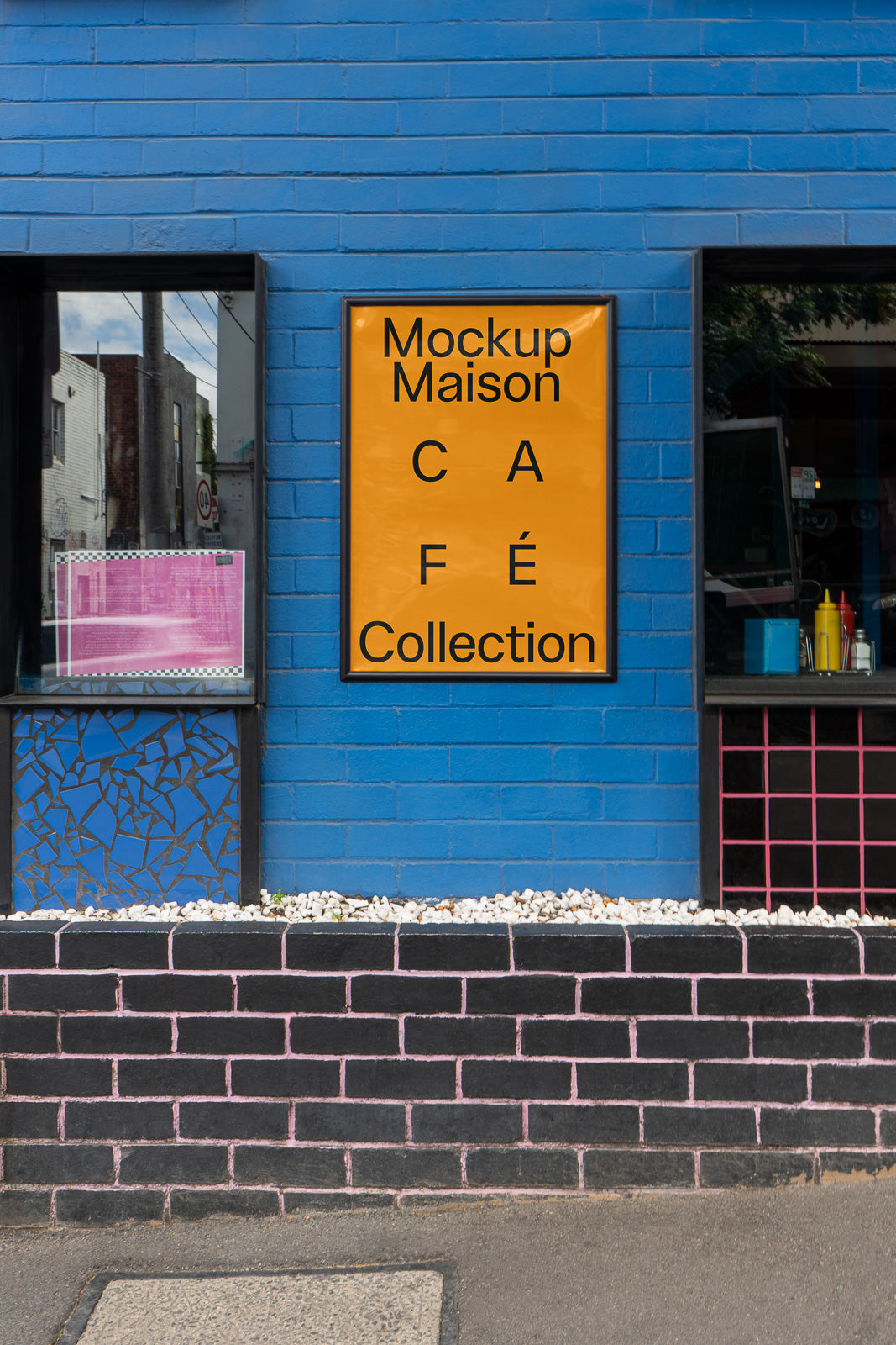 PSD mockup of an exterior brick wall featuring a bright orange poster with bold black text reading "Mockup Maison Café Collection" on a blue wall.