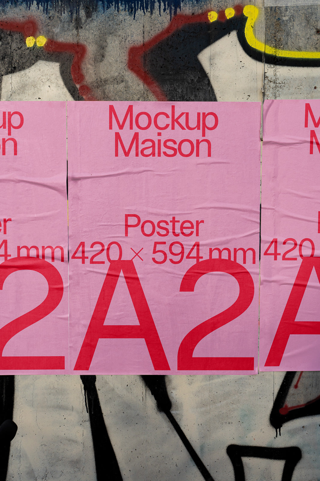 PSD mockup of three pink A2 posters with "Mockup Maison" and "420 x 594 mm" text, set against a graffiti-covered concrete wall background.