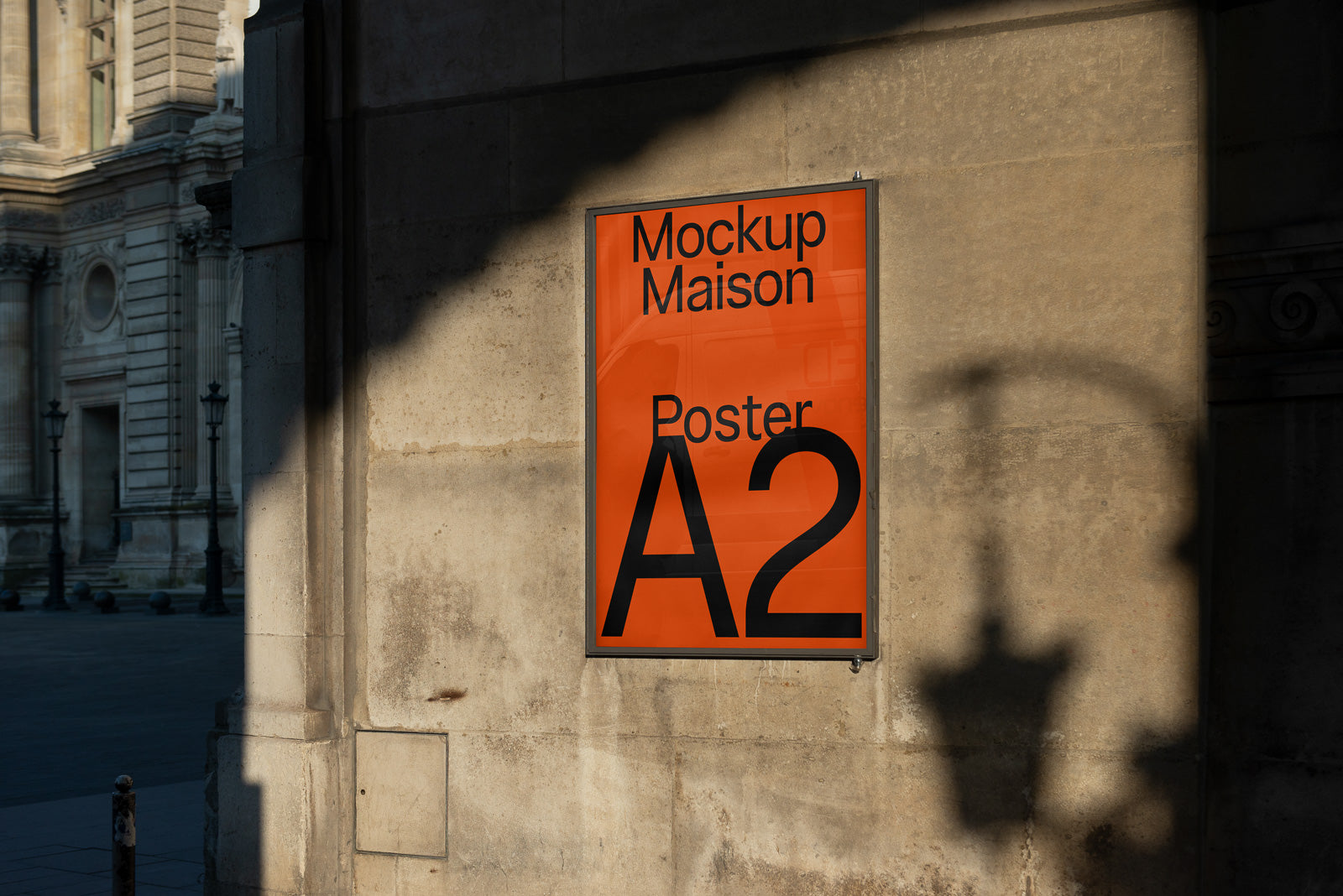 PSD mockup of an A2 poster displayed on an orange background against an urban stone wall, with shadows cast by streetlights.