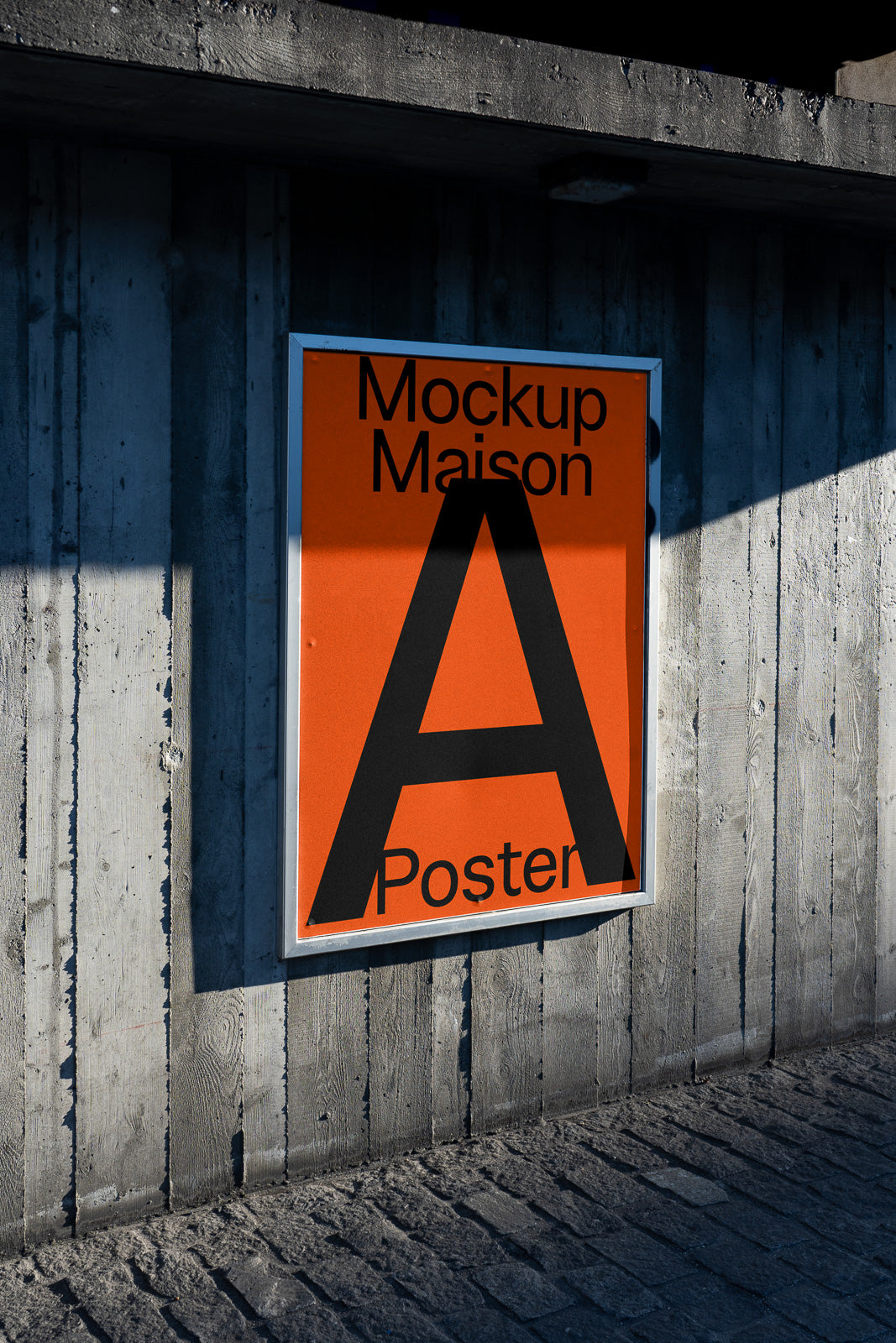 PSD mockup of an orange poster with bold black text reading "Mockup Maison A Poster," displayed on a textured concrete wall.