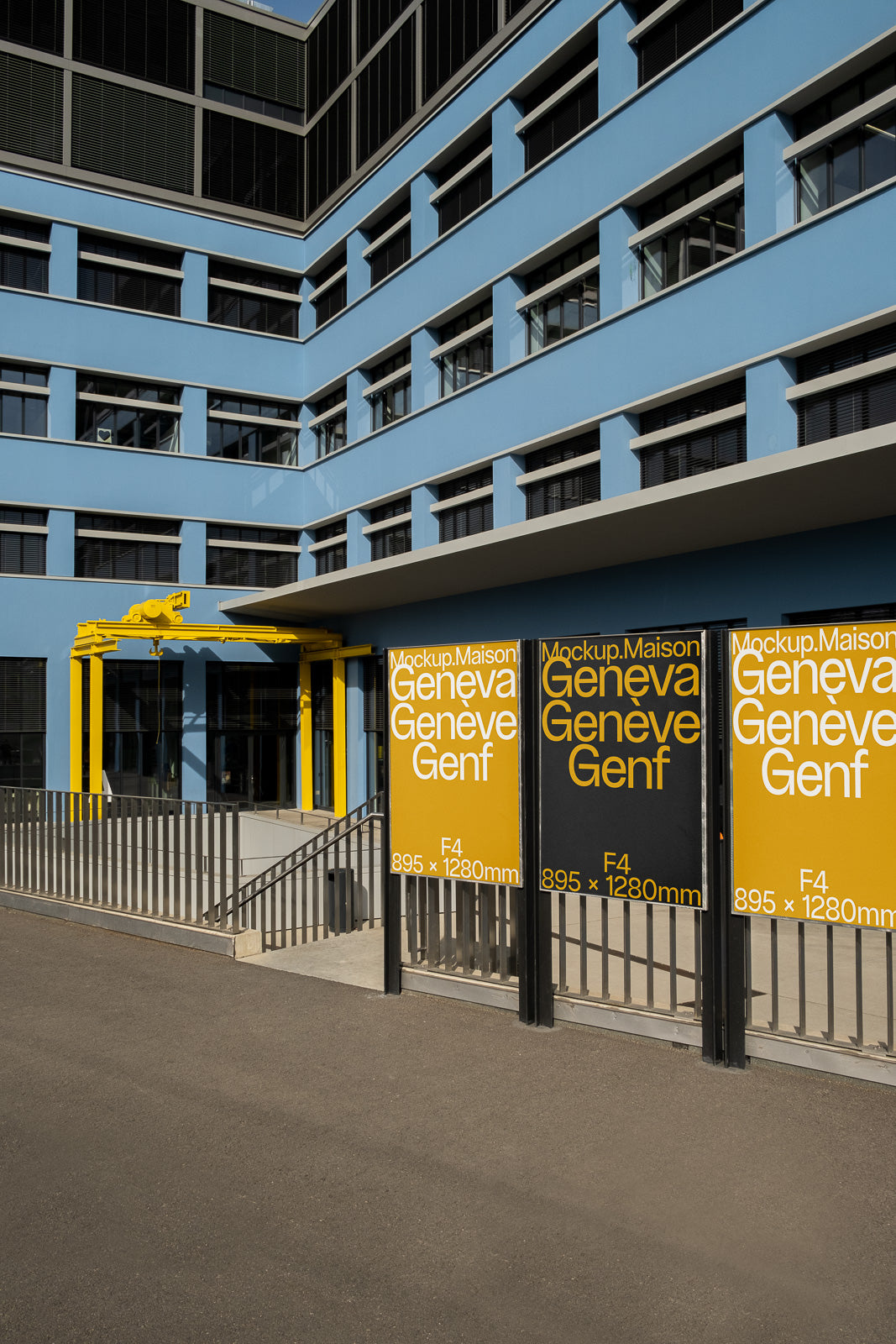 PSD mockup of an urban building exterior with large yellow and black posters displaying text and dimensions on a fence in the foreground.