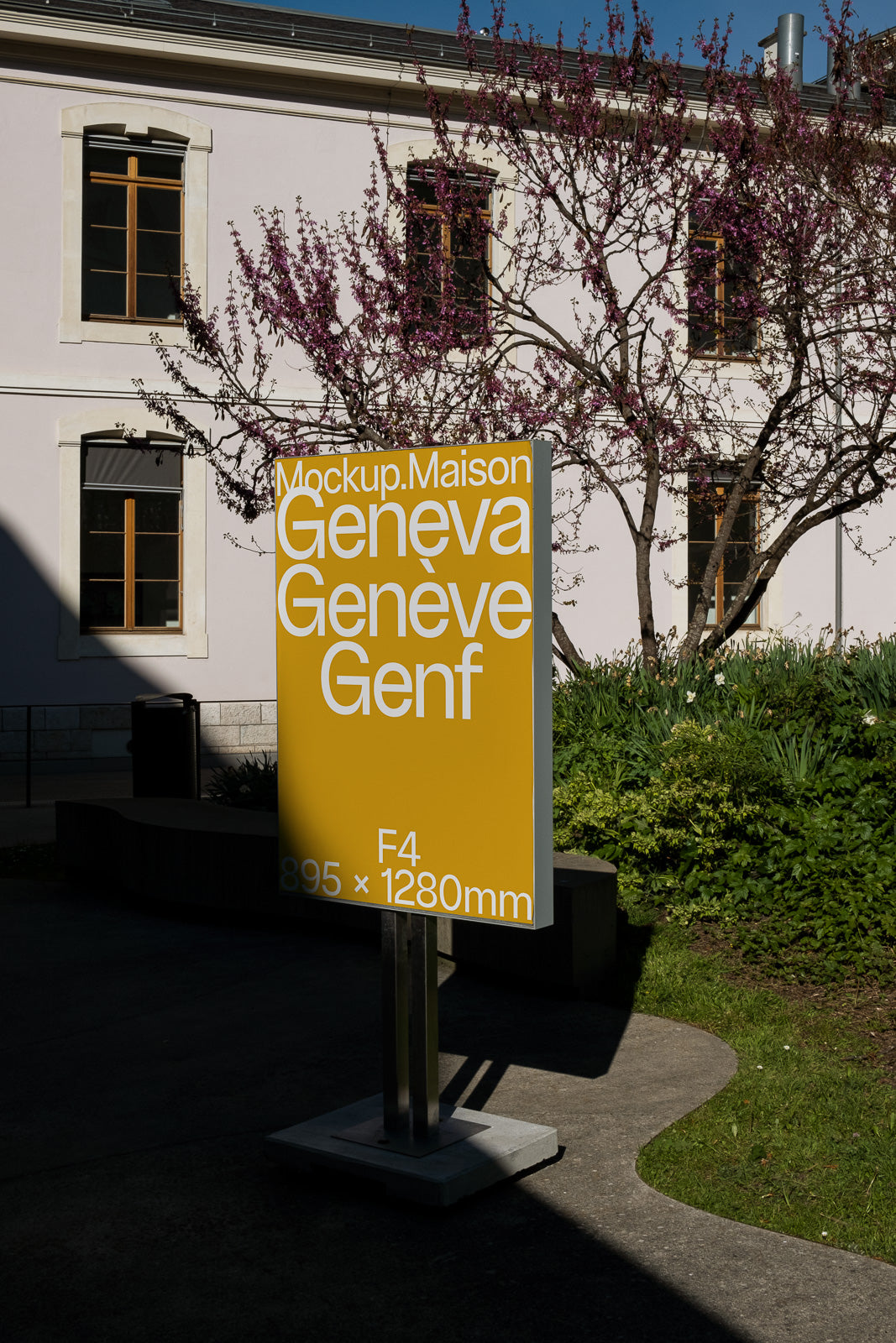 PSD mockup of an outdoor sign with yellow background displaying text "Mockup.Maison Geneva Genève Genf" near a building and blooming tree.