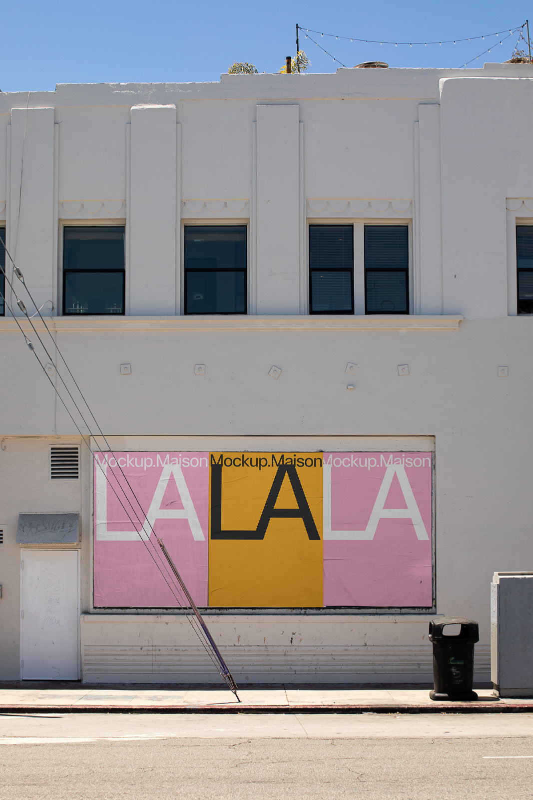 PSD mockup of an urban building facade featuring a large LA LA sign with pink and yellow rectangular backgrounds below windows in an industrial style.