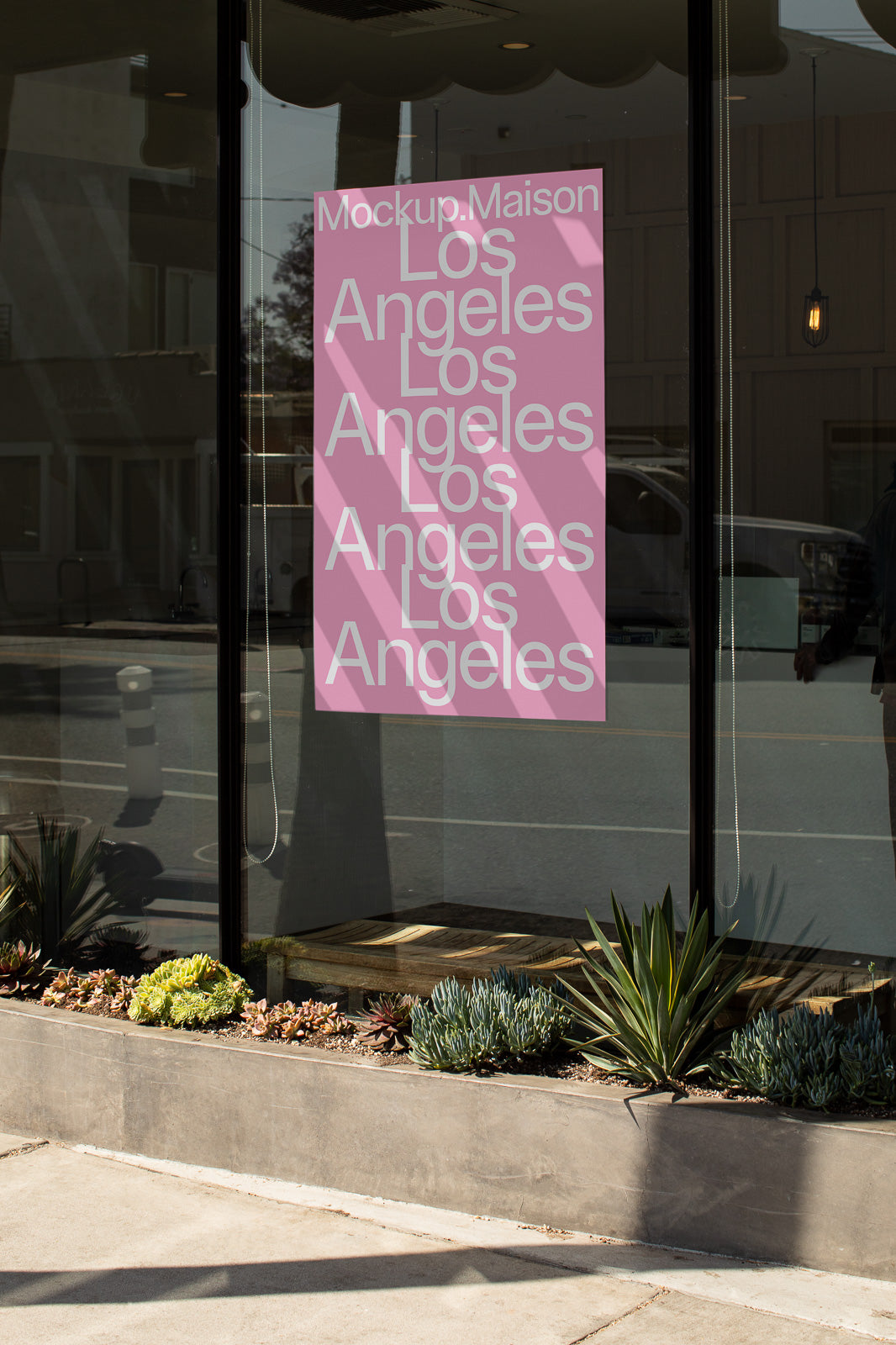 PSD mockup of a pink poster with "Los Angeles" text in white on a storefront window, surrounded by urban plants and reflecting the street.