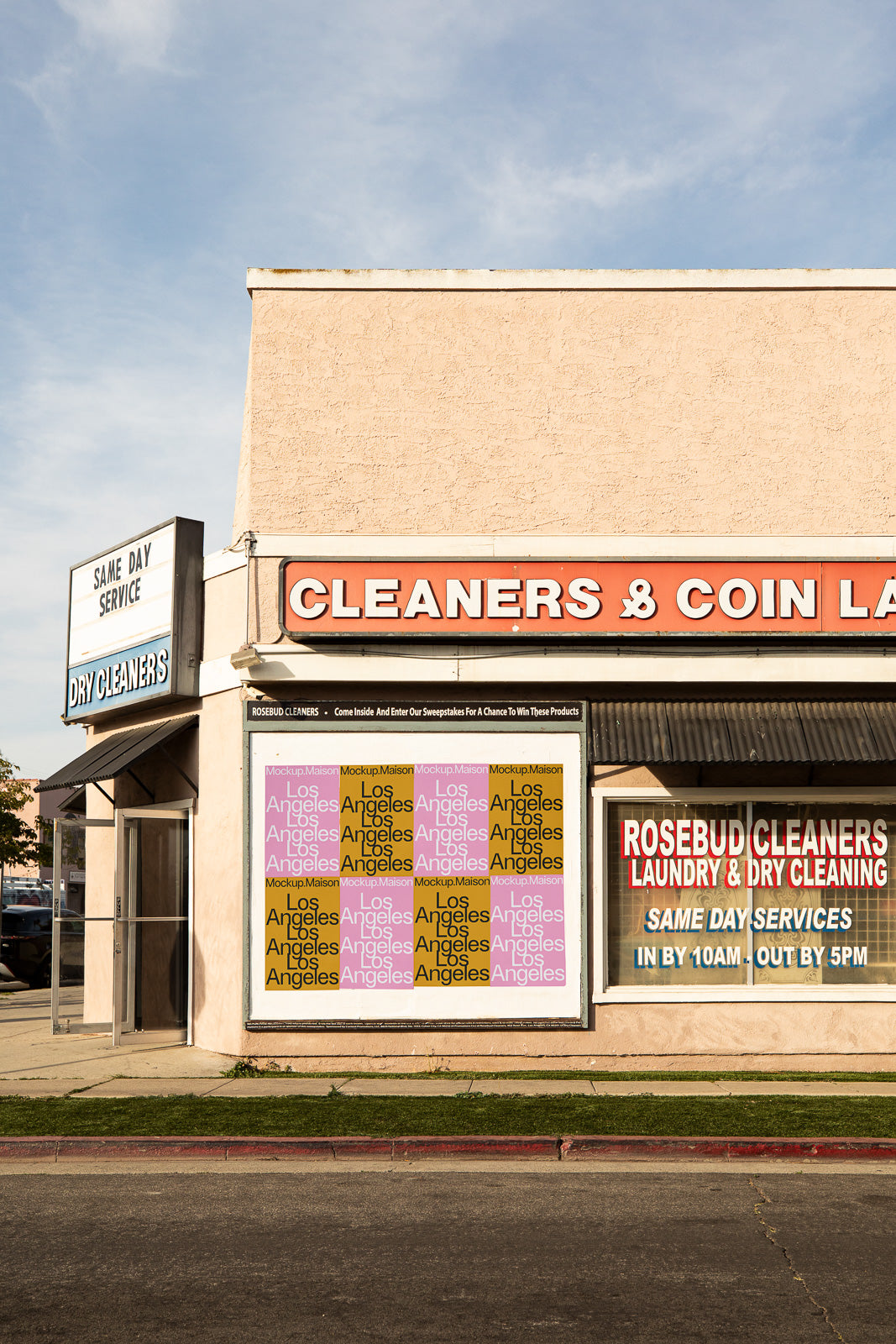 PSD mockup of a dry cleaners storefront featuring a large exterior wall billboard with “Los Angeles” text, under a clear blue sky.