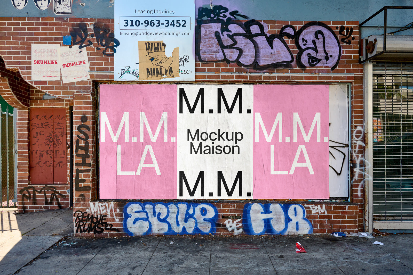 PSD mockup of a street scene with a pink and white poster reading "M.M. Mockup Maison" on a brick wall with graffiti.