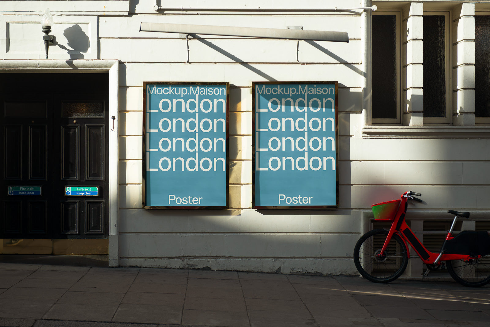 PSD mockup of two framed posters on a building wall with a red bicycle parked nearby, displaying text "Mockup.Maison London" in a vertical layout.