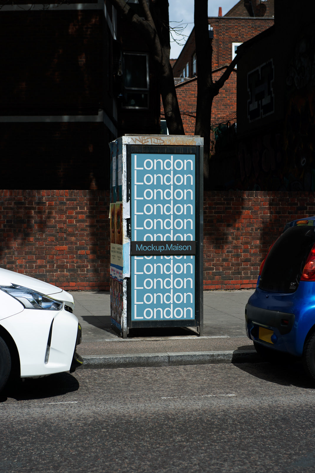 PSD mockup of a street advertisement kiosk with repeated "London" text on a busy urban sidewalk, surrounded by parked cars and brick buildings.