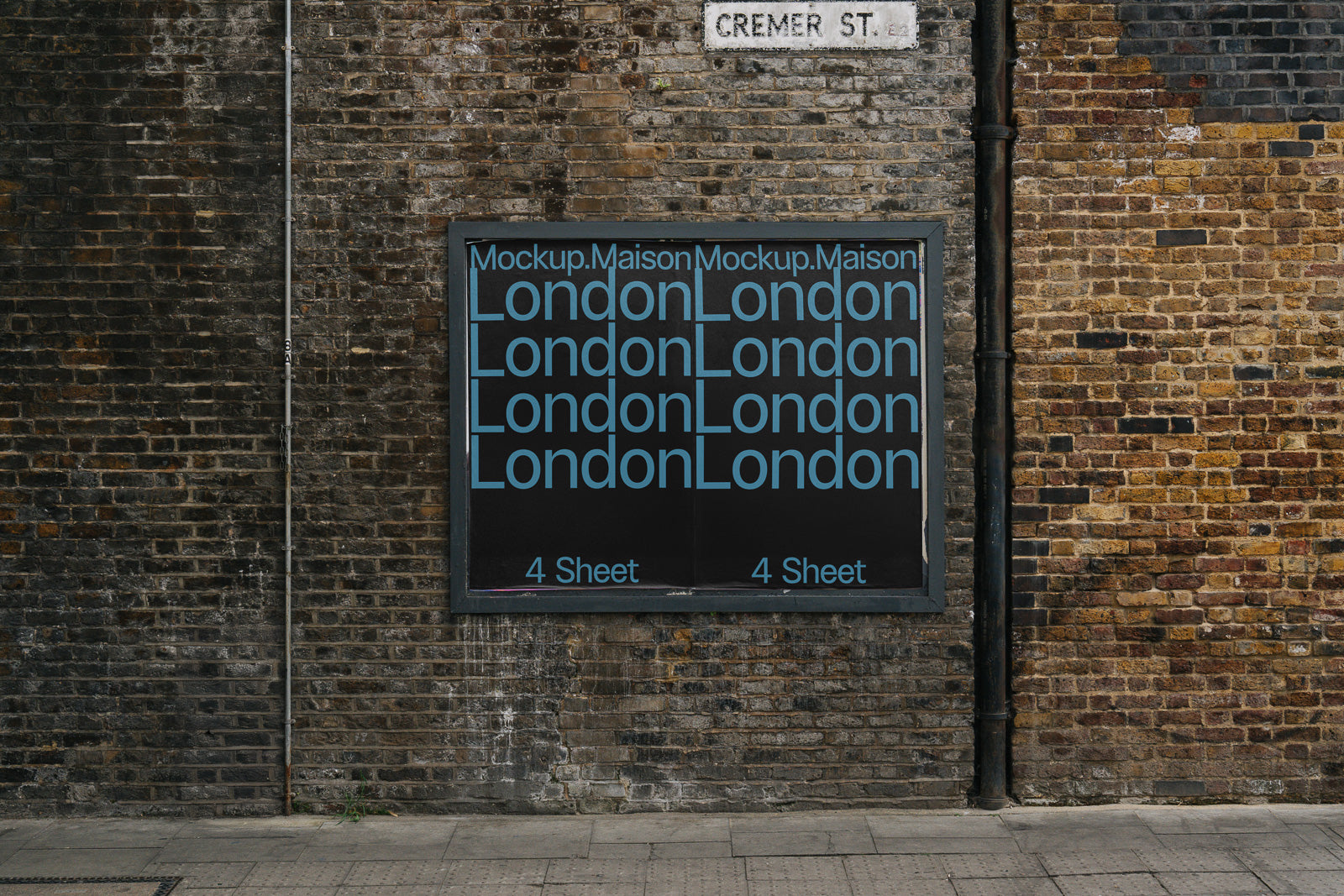 PSD mockup of a vintage brick wall showcasing multiple "London" text lines in blue on a black poster, located beneath a "Cremer St." sign.