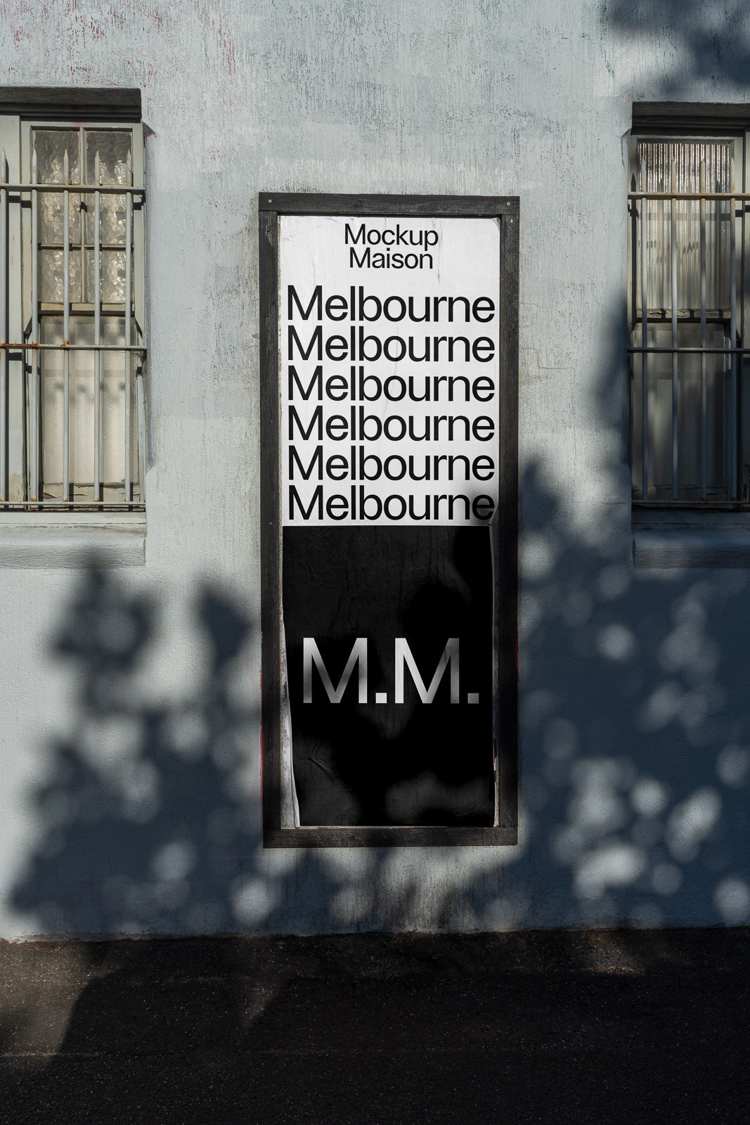 PSD mockup of a wall poster displaying repeated text "Melbourne" and the initials "M.M." in a modern font, framed by a building facade.