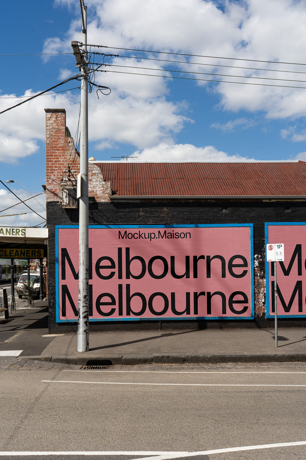 PSD mockup of a large street billboard featuring the text "Melbourne" on a pink background with "Mockup.Maison" above it, set against an urban backdrop.
