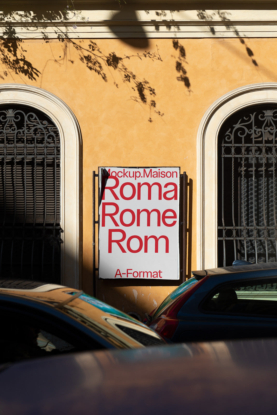 PSD mockup displaying a poster with the text "Roma Rome Rom" against a yellow wall between two arched windows with intricate grilles.