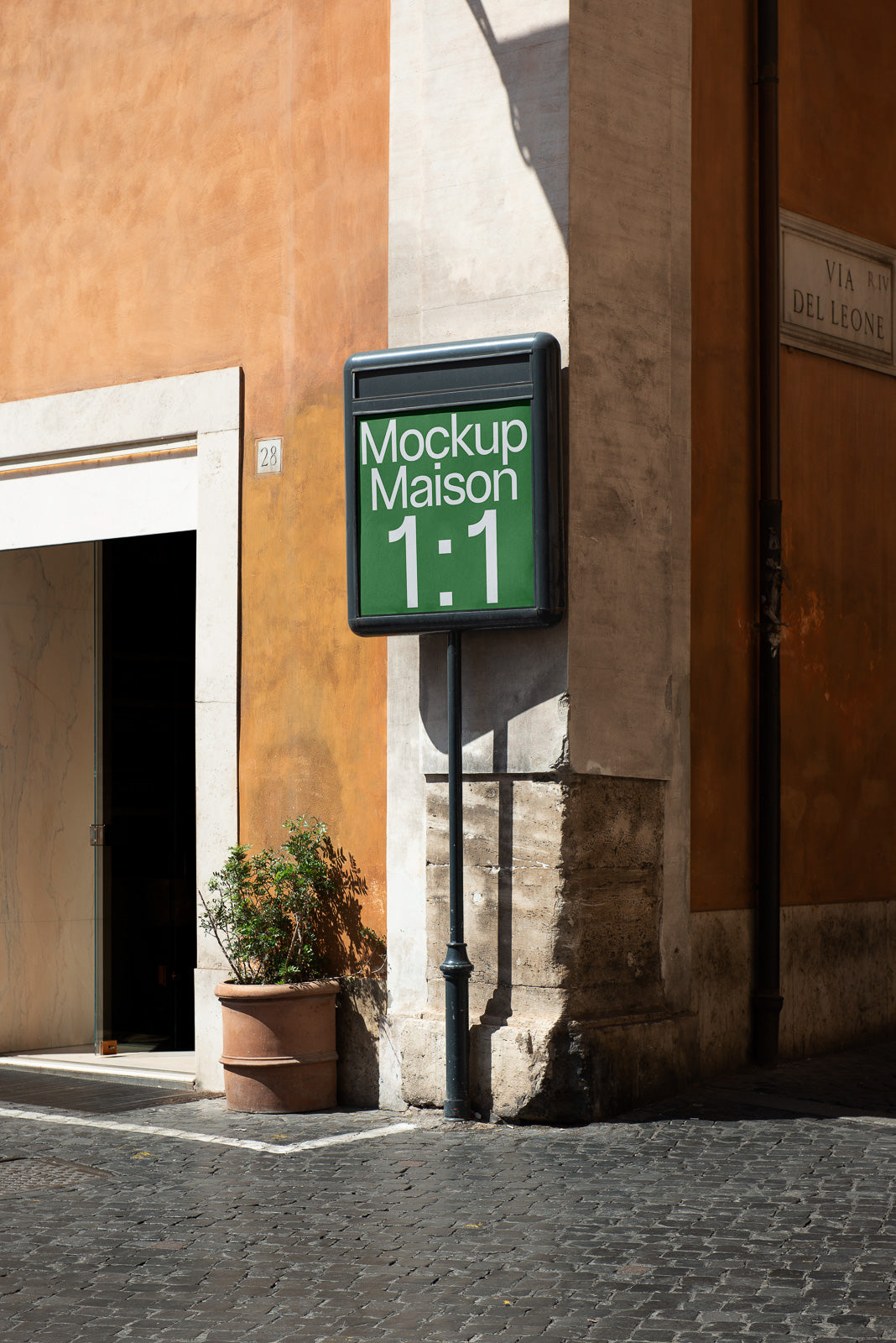 PSD mockup of a vertical signboard on a street corner, displaying "Mockup Maison 1:1" against a textured building with an orange facade.