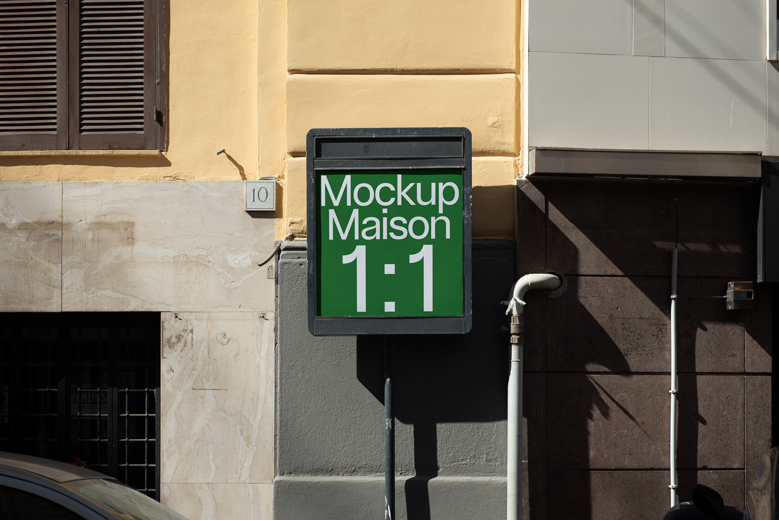 PSD mockup of a building sign with the text "Mockup Maison 1:1" in white on a green background, mounted on a beige and gray wall.
