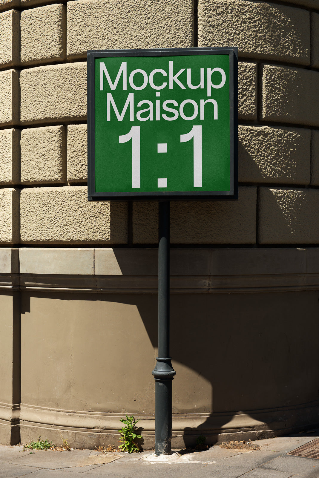 PSD mockup of a street sign attached to a pole at a corner of a textured building, displaying the text "Mockup Maison 1:1" in white on a green background.