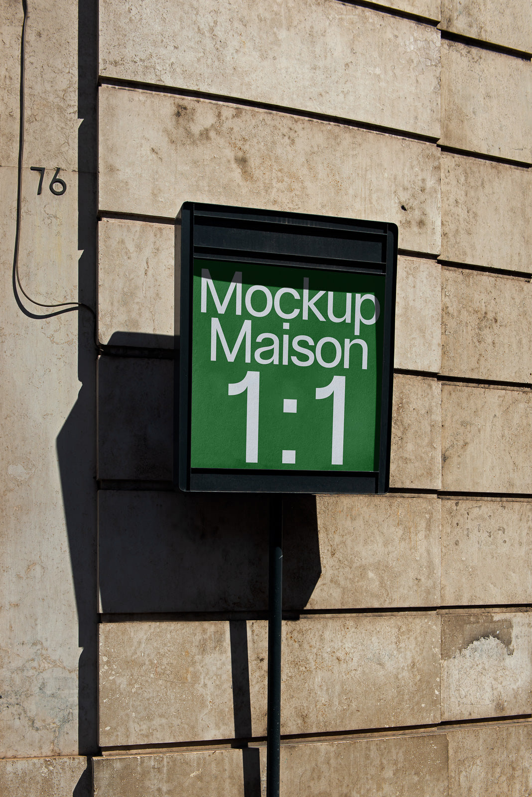 PSD mockup of a rectangular sign with "Mockup Maison 1:1" displayed in bold white text against a green background, mounted on a textured wall.