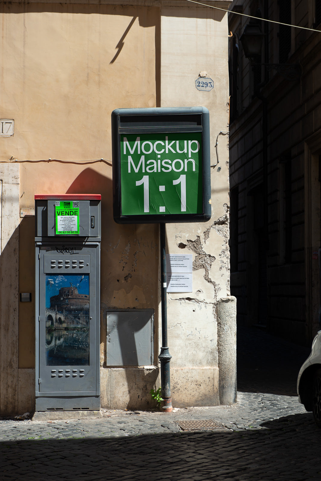 PSD mockup of an outdoor advertisement sign with "Mockup Maison 1:1" displayed against a weathered building wall in a sunlit urban setting.