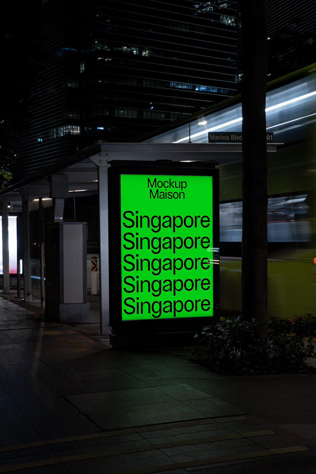 PSD mockup of an urban bus stop at night with a glowing green advertisement displaying "Singapore" multiple times and "Mockup Maison" on top.
