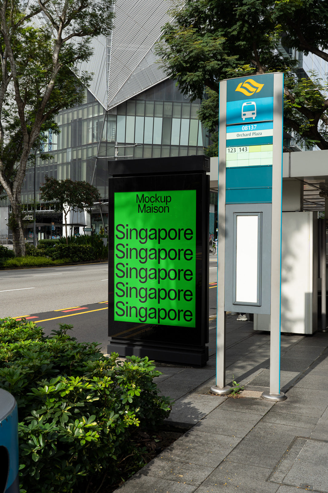 PSD mockup of a bus stop advertising display showing the word Singapore repeatedly on a green background, located next to a modern building and a bus stop sign.