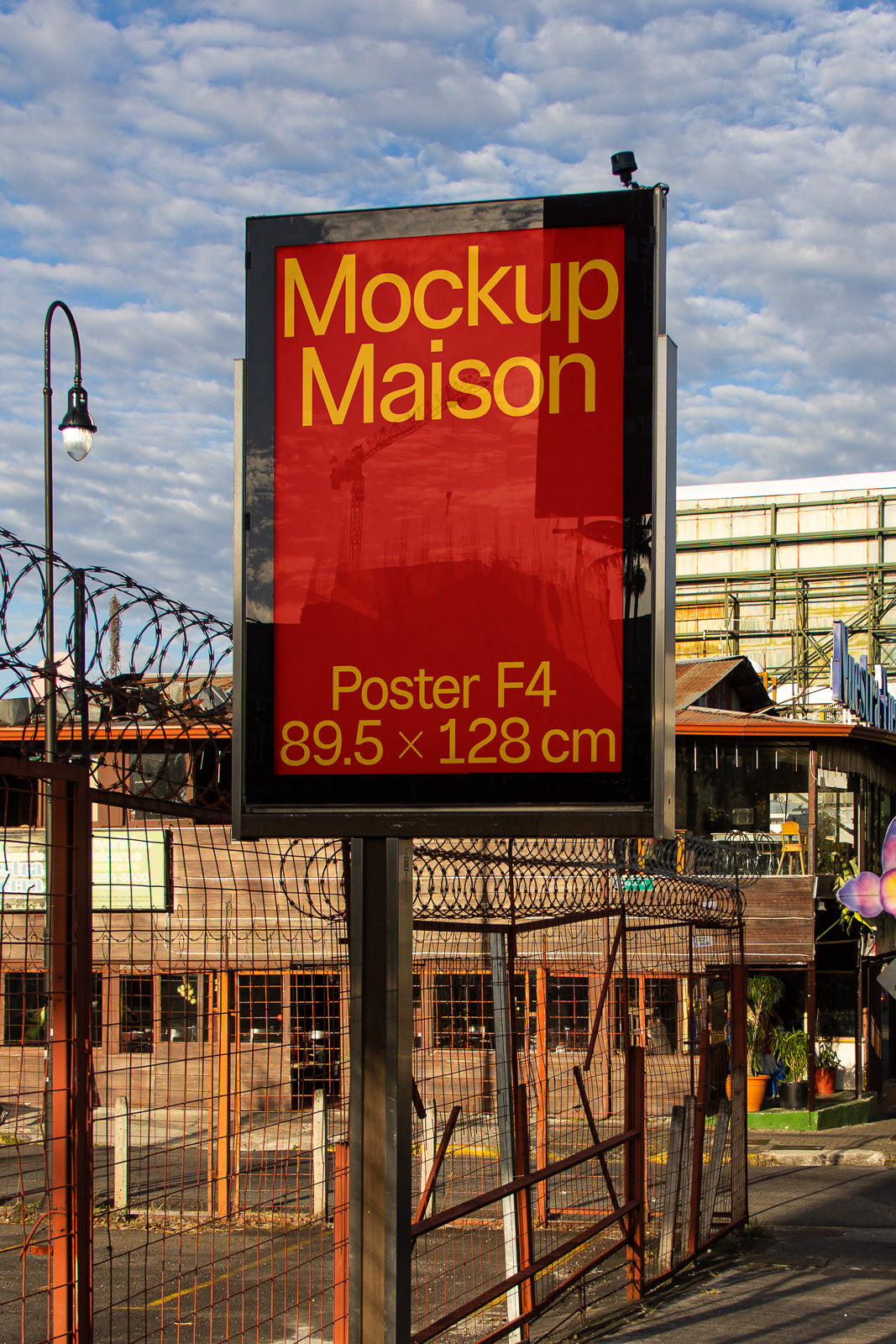 PSD mockup of an outdoor advertising sign with red background, displaying "Mockup Maison" and "Poster F4, 89.5 x 128 cm" text against a city backdrop.