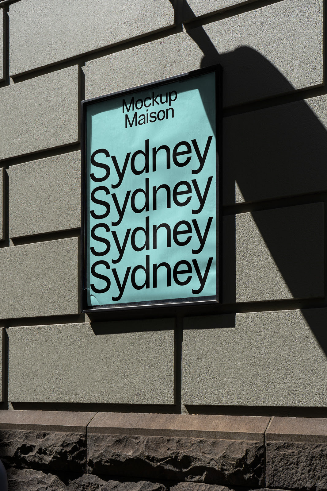 PSD mockup of a framed poster on a wall with the word "Sydney" repeated in bold black text against a light blue background.