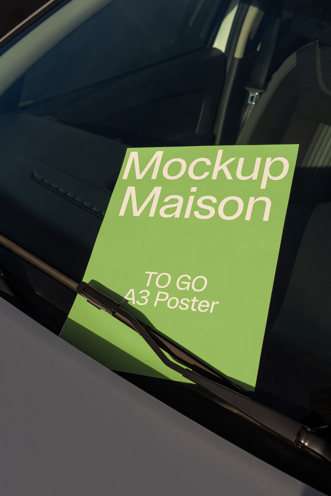 PSD mockup of a green A3 poster reading "Mockup Maison TO GO" placed under the windshield wiper of a car in daylight.