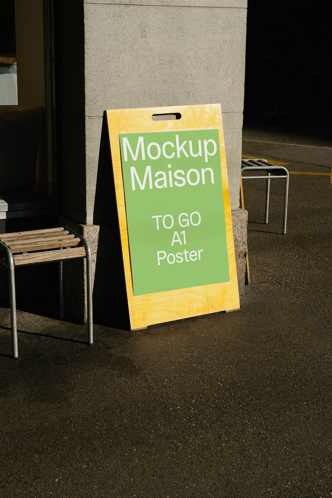 PSD mockup of a green A1 poster sign leaning against a concrete wall, casting a shadow on the ground, with chairs in the background.
