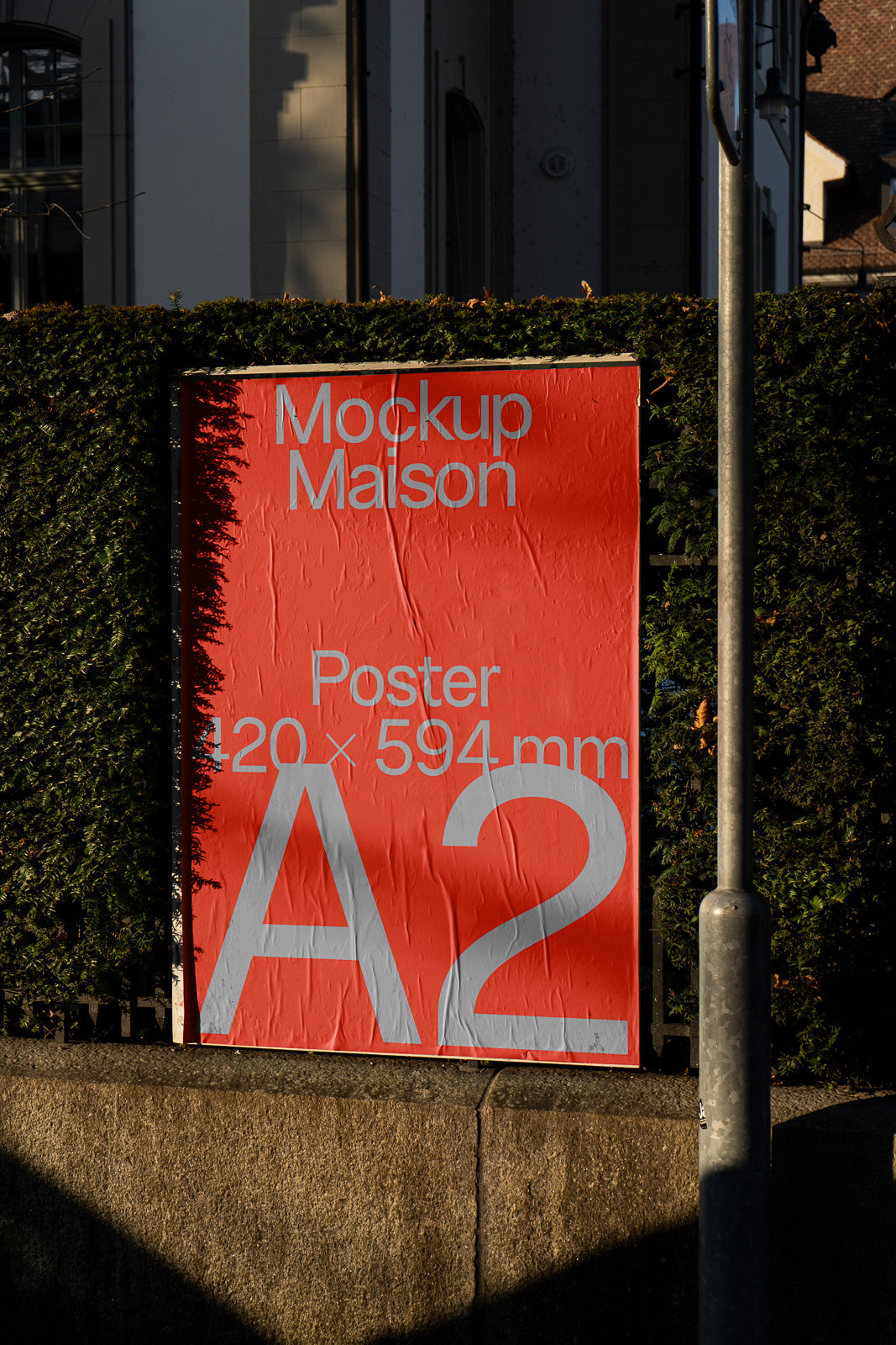 PSD mockup of a red A2 poster with "Mockup Maison" text, displayed outdoors against a hedge, with dimensions 420 x 594 mm.