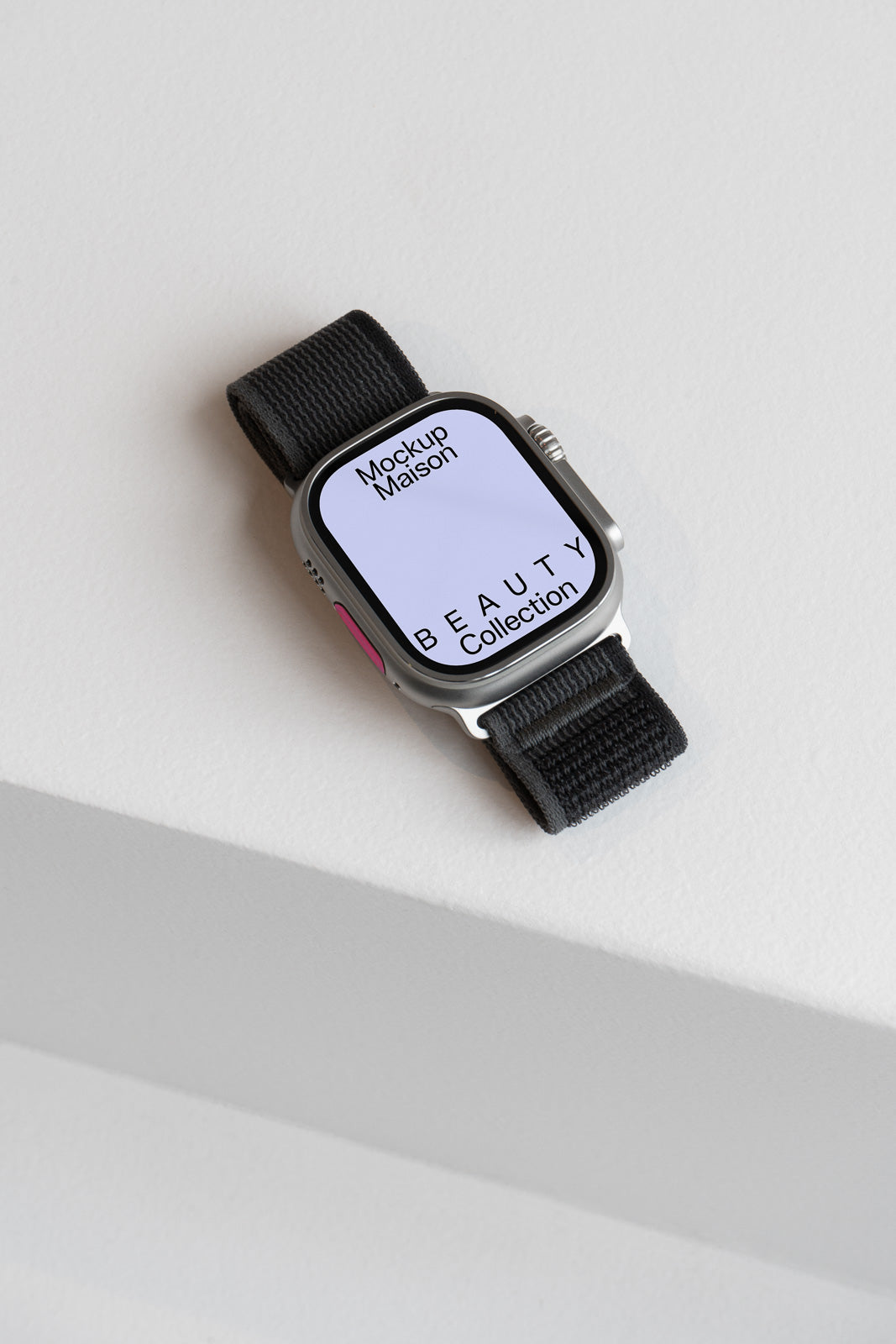 PSD mockup of a smartwatch with a black woven band displaying "Beauty Collection" text on the screen, placed on a light surface.