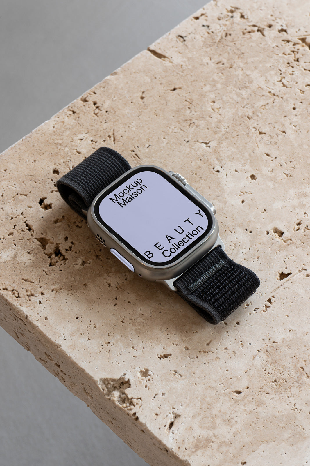 PSD mockup of a smartwatch with a black band on a beige stone surface, displaying "Mockup Maison" and "BEAUTY Collection" on the screen.