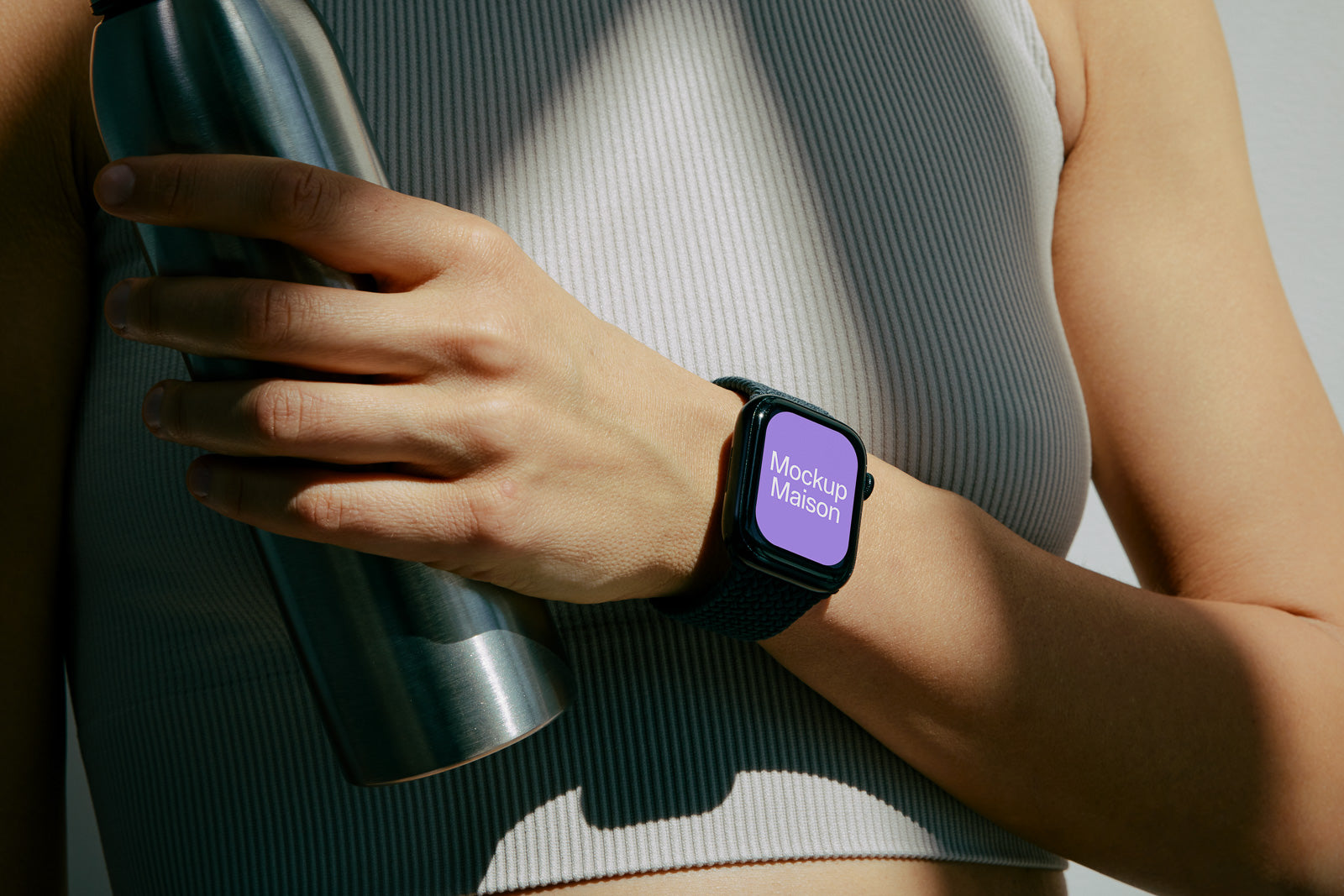 PSD mockup of a smartwatch with a lavender display reading "Mockup Maison" worn by a person holding a stainless steel water bottle against their torso.